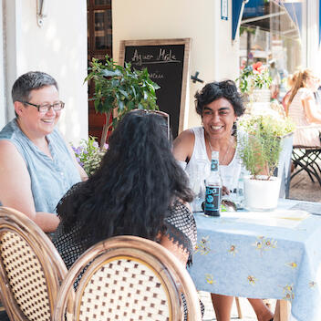 Vor der Tür des Feinkosthandels Meile sitzen Freundinnen und lachen